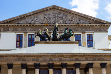 The building of National Opera House in Warsaw (also known as Opera Narodowa, Teatr Wielki) with statue of Apollo on horse drawn chariot and relief pediment architecture - obrazy, fototapety, plakaty