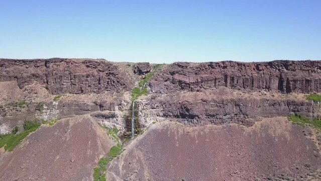 Aerial approach to small rock canyon waterfall in Frenchman Coulee