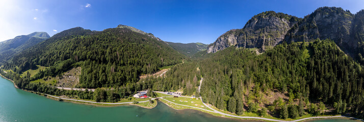 Wide panorama of Montriond lake seen from above. Aerial of French Alps mountain range and leisure...