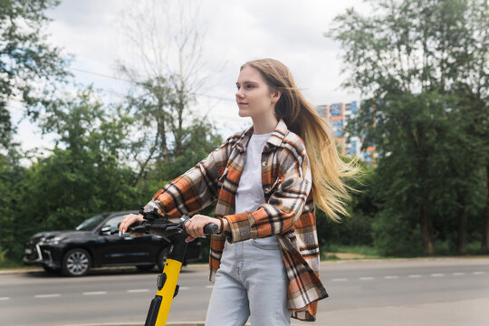 young woman on an electric scooter rides down the street