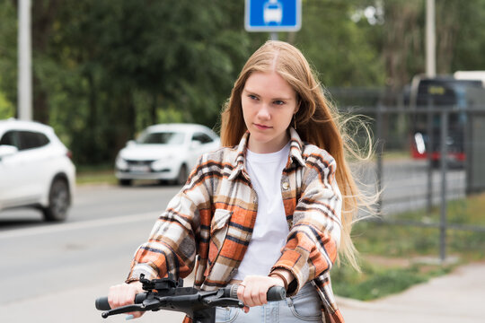 young woman on an electric scooter rides down the street
