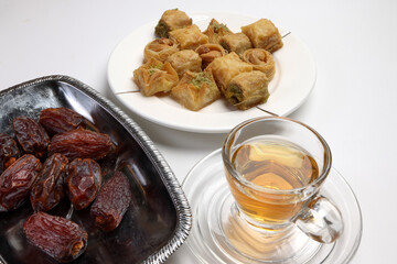 Layered stuffed pastry Baklava middle eastern sweet dessert dry ripe sweet date fruit tea in transparent glass cup saucer on white background