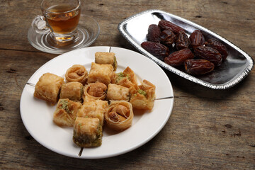 Layered stuffed pastry Baklava middle eastern sweet dessert dry ripe sweet date fruit tea in transparent glass cup saucer on rustic wooden background