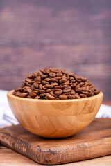 Coffee bean on wood background. Coffee bean in wooden bowl. Close up