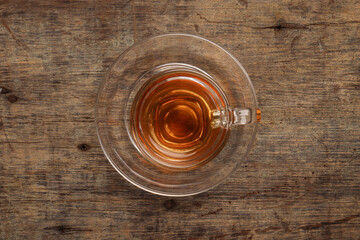 Hot tea in transparent glass cup saucer on rustic wood background