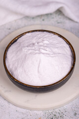 Sodium bicarbonate or baking soda on grey background. Sodium bicarbonate powder in bowl