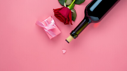Top view of Valentines Day gift with wine and pink rose bouquet on pink background design concept