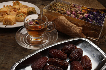 Baklava sweet dessert  date fruit liquid honey natural geomatic hexagon bee wax honeycomb flower tea rose bud butterfly pea chamomile flower tea in transparent glass cup saucer on rustic wood table ba