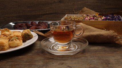 Baklava sweet dessert  date fruit liquid honey natural geomatic hexagon bee wax honeycomb flower tea rose bud butterfly pea chamomile flower tea in transparent glass cup saucer on rustic wood table ba