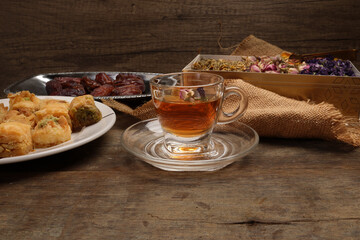 Baklava sweet dessert  date fruit liquid honey natural geomatic hexagon bee wax honeycomb flower tea rose bud butterfly pea chamomile flower tea in transparent glass cup saucer on rustic wood table ba
