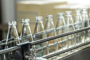 Empty glass bottles on the conveyor. Factory for bottling alcoholic beverages. The bottles on the conveyor belt at the plant for bottling of Juice
