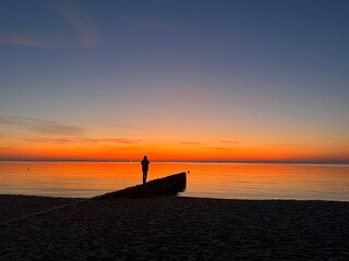 Lonely human silhouette at the sea beach, orange sea horizon, twilights