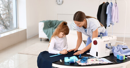 Little daughter helping her mother in tailor's workshop