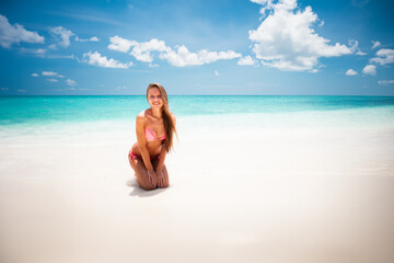 Young attractive blonde girl with perfect sport body in bikini on the tropical summer beach