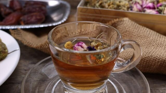 Baklava sweet dessert  date fruit liquid honey natural geomatic hexagon bee wax honeycomb flower tea rose bud butterfly pea chamomile flower tea in transparent glass cup saucer on rustic wood table ba