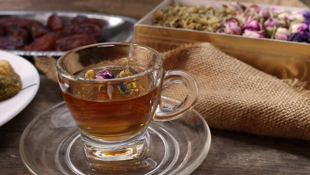 Baklava sweet dessert  date fruit liquid honey natural geomatic hexagon bee wax honeycomb flower tea rose bud butterfly pea chamomile flower tea in transparent glass cup saucer on rustic wood table ba