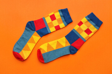 Pair of stylish socks on orange background
