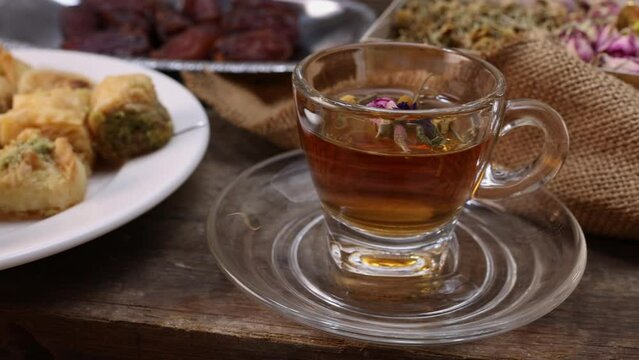 Baklava sweet dessert  date fruit liquid honey natural geomatic hexagon bee wax honeycomb flower tea rose bud butterfly pea chamomile flower tea in transparent glass cup saucer on rustic wood table ba
