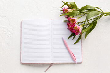 Naklejka premium Blank open notebook with pen and alstroemeria flowers on light background