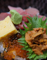 close up of delicious fresh ikura salmon egg, uni sea urchin, maguro tuna, sweetened egg and wasabi on top of japanese rice dong 