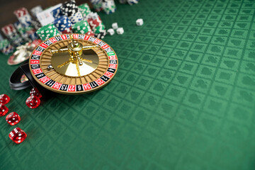 Casino. Gambling games theme.  Roulette wheel, dice and poker chips on the casino felt green table.