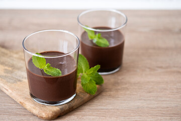 Chocolate mousse dessert garnished with mint leaf on wooden table and white background. Copy space