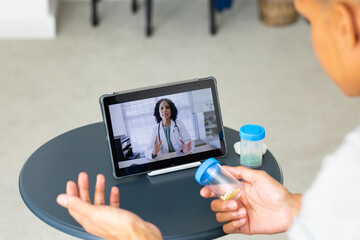 Close up of biracial man using tablet for consultation video call with biracial female doctor