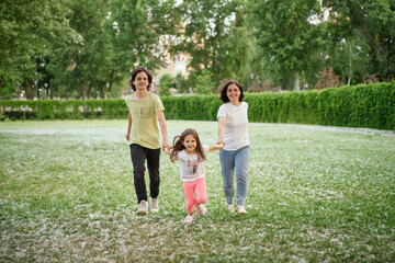 Smiling Family Running Across Summer Field Together. Mother Daughter son, hands together High quality photo