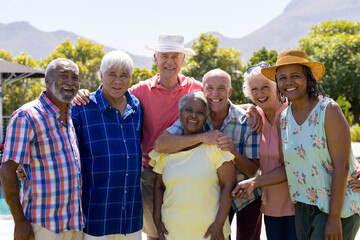Portrait of happy senior diverse people embracing and smiling in garden