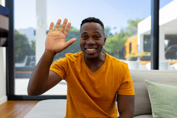 Happy african american man sitting on sofa and having video call
