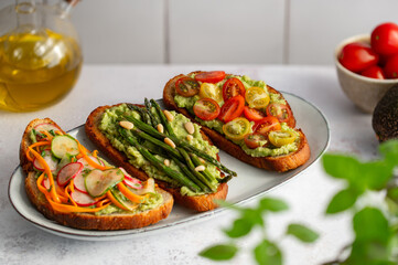 Toasted sourdough bread with grilled asparagus, avocado, tomatoes, radish and herbs for single serving. Avocado toast. Breakfast idea. Healthy food concept.