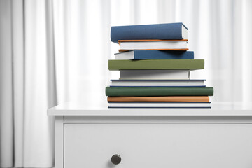 Hardcover books on white chest of drawers indoors