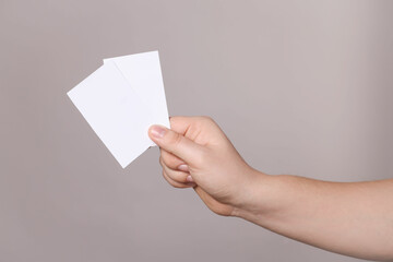 Woman holding paper cards on grey background, closeup. Mockup for design