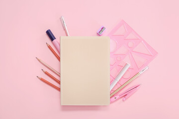 Notebook with different stationery on pink background