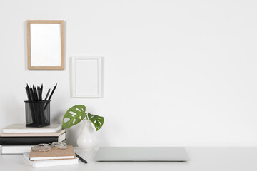 Obraz na płótnie Canvas Cozy workspace with laptop, houseplant and stationery on white desk at home