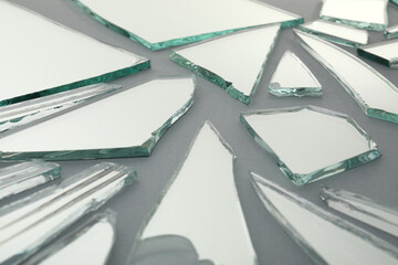 Shards of broken mirror on grey background, closeup