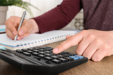 Man calculating pension at wooden table, closeup