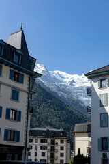 Eternal snow on the Mont Blanc massive rising above the buildings of ski village Chamonix in the French Alps against a clear blue sky.