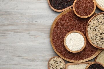 Dishes with different sorts of rice on white wooden table, flat lay. Space for text