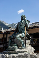 Obraz premium Sculpture in picturesque town in French Alps with cultural heritage and snow tops of mountians in the background. Tourist and outdoor winter sports destination