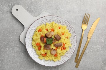 Delicious pilaf with meat served on light grey table, flat lay