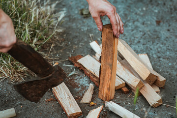 Chopping wood for the fire with an axe. A man's hand with an axe chopping wood, close-up. Preparing...