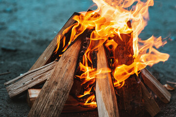 A bright flame of fire over a campfire. Wooden wood stacked in a pyramid is burning. The flame of...