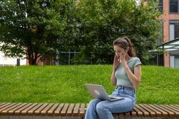 Young woman using laptop computer in park, freelance student girl working and studying online outdoors