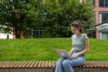 A young woman is using a laptop and a smartphone. beautiful student girl working on laptop outdoor