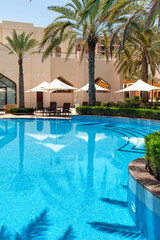 Swimming pool with clear water surrounded by palm trees in one of the best resorts