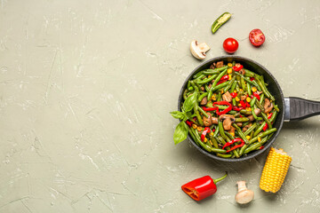 Frying pan with different vegetables on light background
