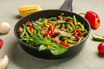 Frying pan with different vegetables on light background