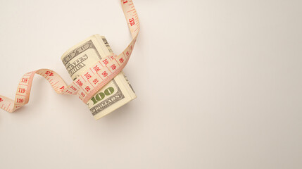 A Symbolic tape measure wrapped around a US dollar banknote captures the economic challenge of the...