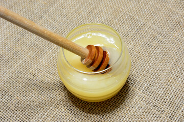 drinking glass with honey and wooden honey deeper isolated, close up  